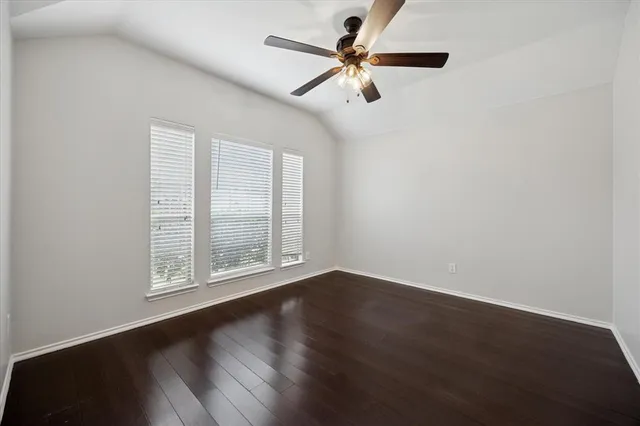 an empty room with wooden floor fan and windows