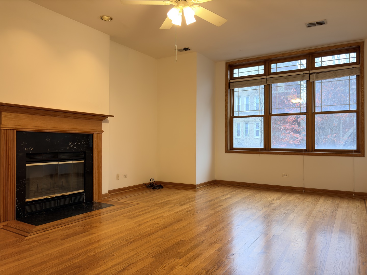 4101 North Kenmore Avenue, Unit 2S Chicago, IL 60613 - Photo 2 of 11 a view of an empty room with wooden floor fireplace and a window