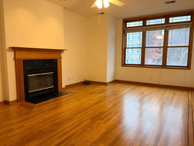an empty room with wooden floor fireplace and windows