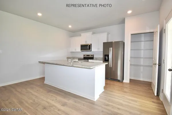 a kitchen with stainless steel appliances granite countertop a refrigerator a stove a sink and a microwave
