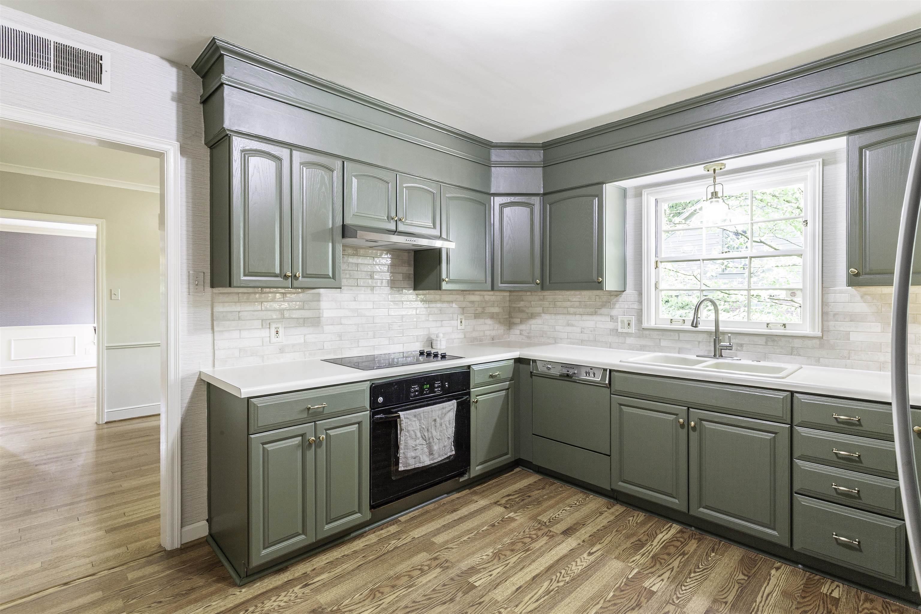 480 Colonial Road Memphis, TN 38117 - Photo 6 of 16 Kitchen featuring green cabinetry, white countertops, tile backsplash, stainless steel appliances, and wood-finish flooring