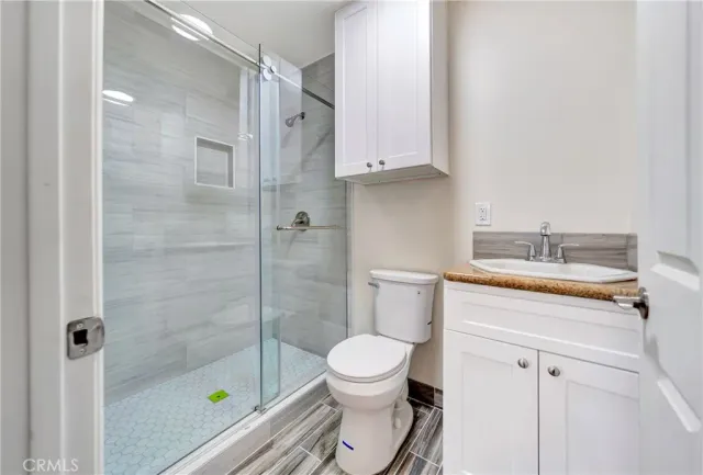 a bathroom with a granite countertop toilet a sink and a shower