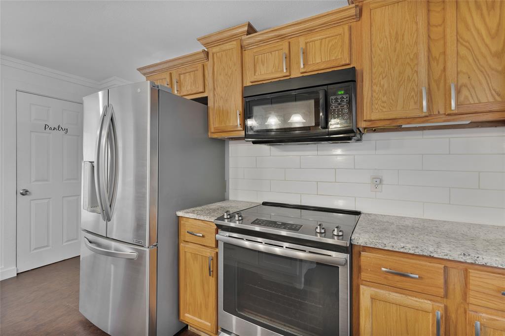 903 Lynn Street Bonham, TX 75418 - Photo 10 of 29 a kitchen with stainless steel appliances white cabinets and a stove top oven