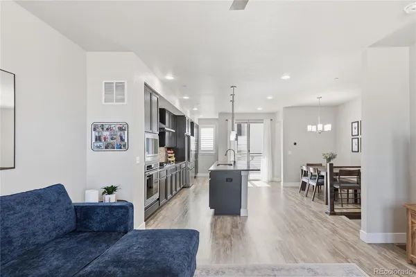 a living room with furniture wooden floor and a kitchen view