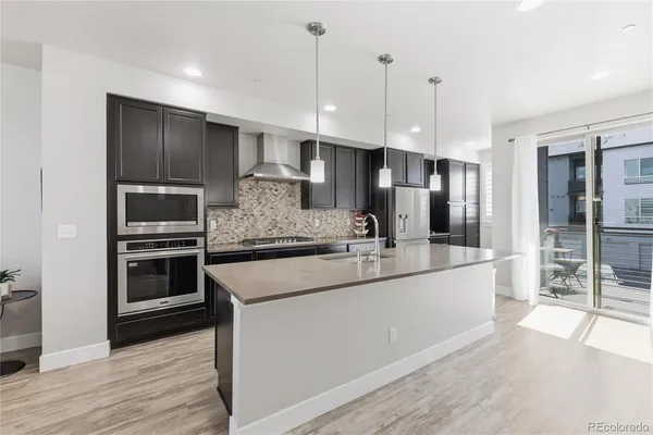 a large kitchen with a large counter top stainless steel appliances and wooden floor