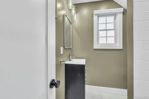 a view of a house with brick walls and a yard with plants and a large tree