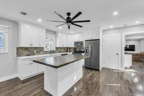 a kitchen with stainless steel appliances granite countertop a sink cabinets and wooden floor