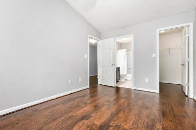 a view of an empty room with wooden floor and a bathroom