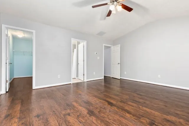 an empty room with wooden floor chandelier fan and windows