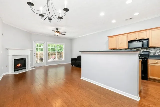 a view of a kitchen with furniture a ceiling fan and wooden floor