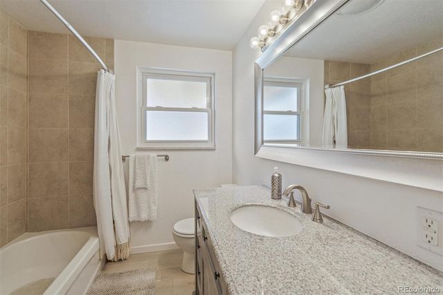 a bathroom with a granite countertop sink a mirror and a bathtub