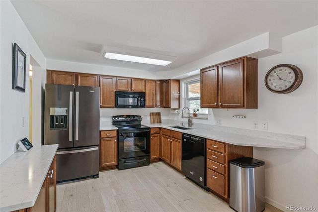 a kitchen with stainless steel appliances granite countertop a refrigerator a stove top oven a sink and dishwasher