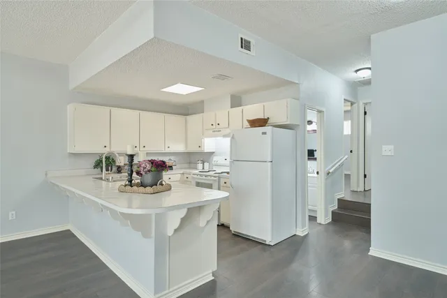 a kitchen with refrigerator and white cabinets