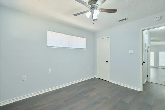 an empty room with a window and a fan