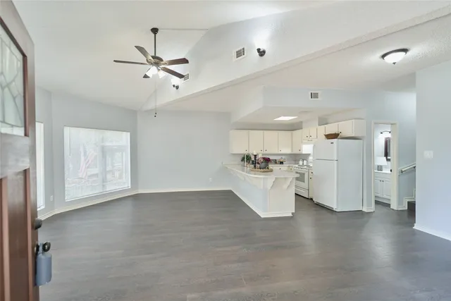 a view of a kitchen with refrigerator and white cabinets