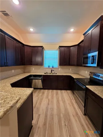 a kitchen with granite countertop wooden cabinets a stove and a granite counter top