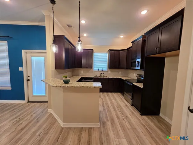 a kitchen with stainless steel appliances granite countertop wooden cabinets a refrigerator a sink and a stove