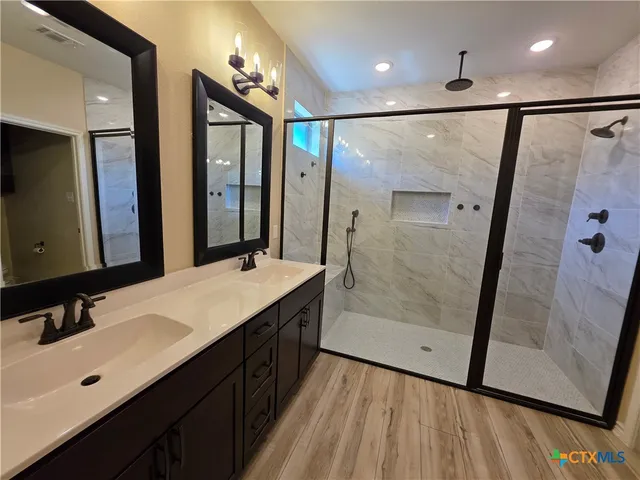 a bathroom with a double vanity sink mirror and shower