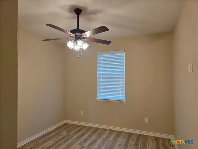 an empty room with a window and a fan