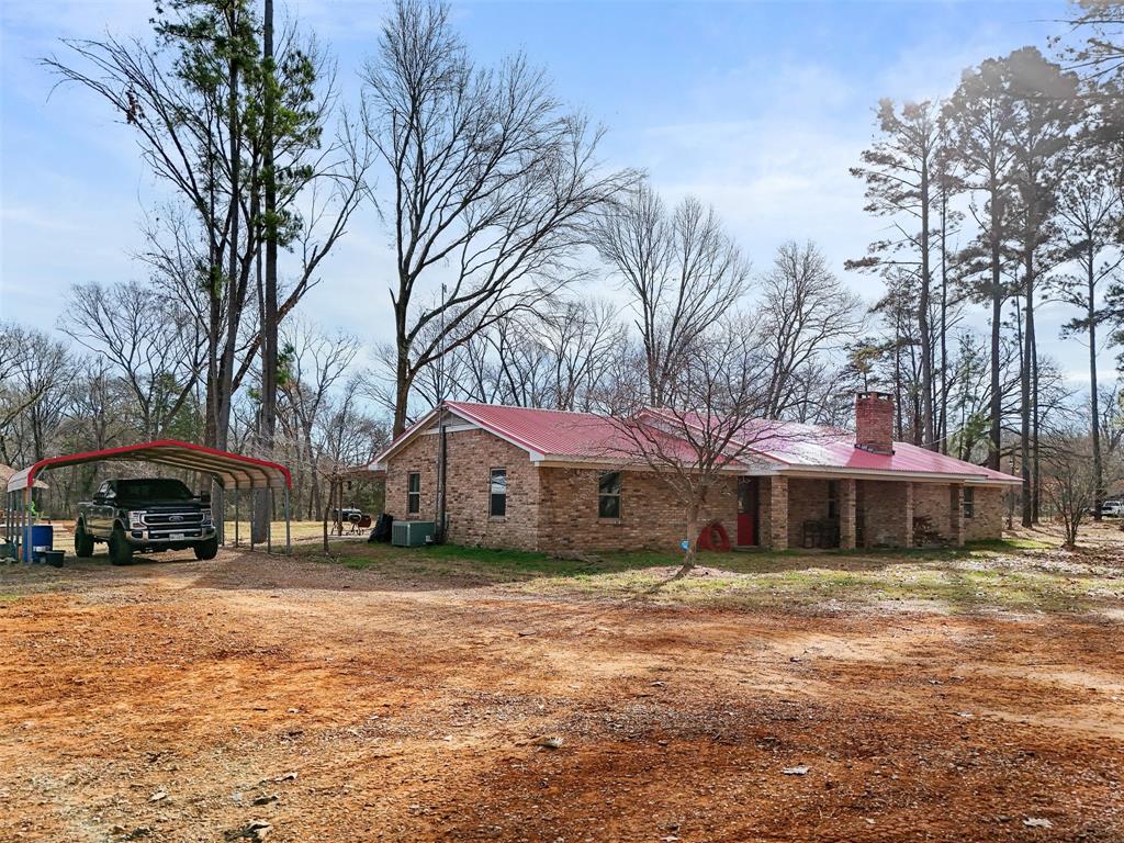 View of home's exterior with a detached carport, a chimney, driveway, and brick siding