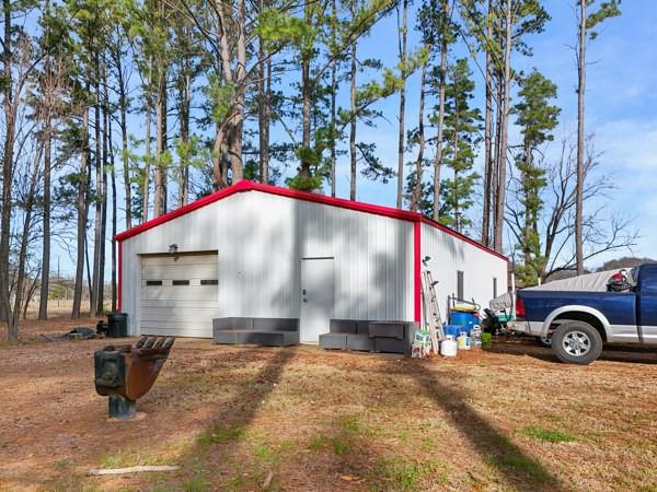 7766 North State Highway 78 Ravenna, TX 75476 - Photo 25 of 39 View of side of home with an outdoor structure, a detached garage, and driveway