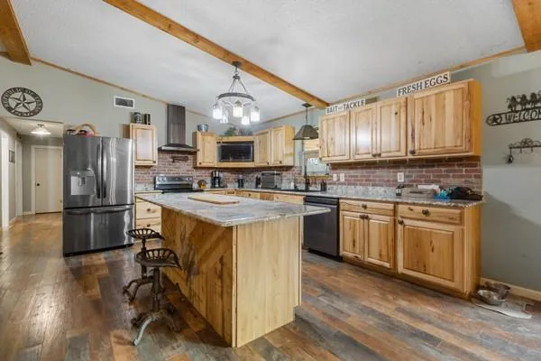 a kitchen with stainless steel appliances granite countertop a refrigerator a stove a sink dishwasher and white cabinets with wooden floor