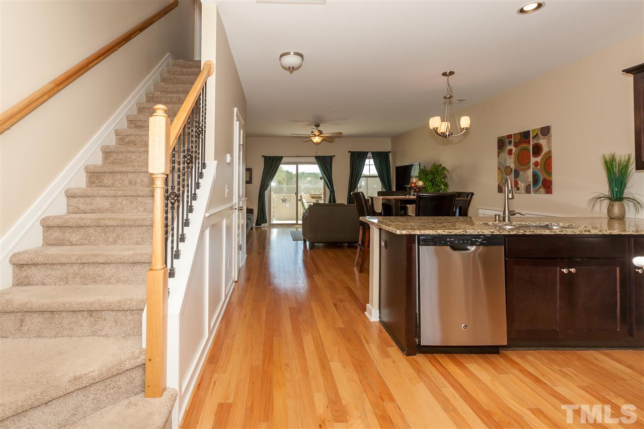 7811 Lillyhurst Drive Raleigh, NC 27612 - Photo 4 of 25 a view of a living room with kitchen island granite countertop wooden floor and a fireplace