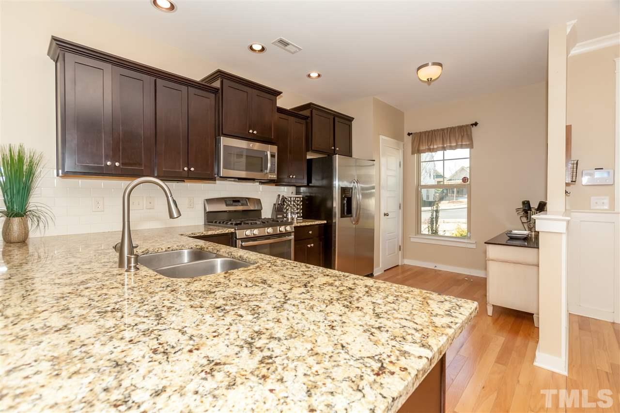 7811 Lillyhurst Drive Raleigh, NC 27612 - Photo 10 of 25 a kitchen with granite countertop a stove a sink and a microwave