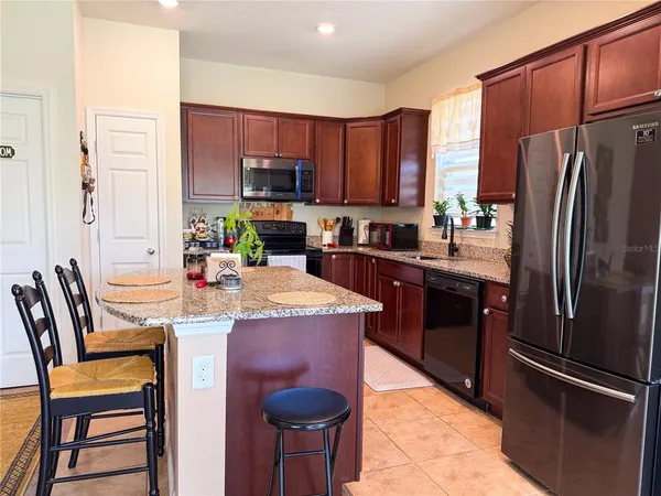 a kitchen with stainless steel appliances granite countertop a refrigerator a stove a sink a dining table and chairs