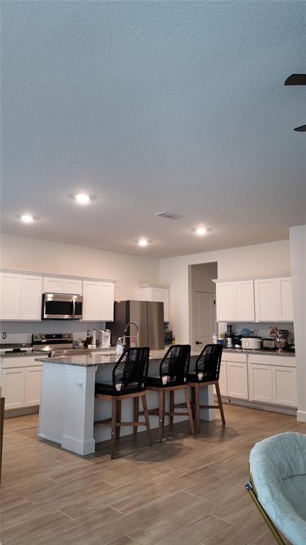 8599 Sportsman Loop Groveland, FL 34736 - Photo 6 of 19 a kitchen with stainless steel appliances kitchen island granite countertop a stove top oven a dining table and chairs with wooden floor