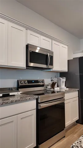 a kitchen with stainless steel appliances granite countertop grey cabinets a stove a sink and dishwasher