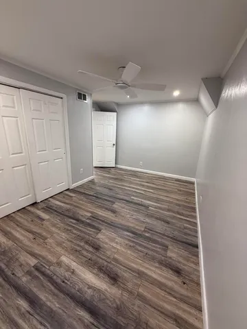 an empty room with wooden floor closet and windows