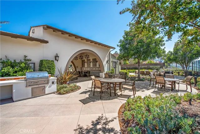 a view of a patio with dining table and chairs with plants and a barbeque