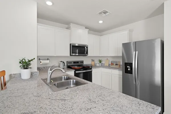 a kitchen with a refrigerator sink and white cabinets