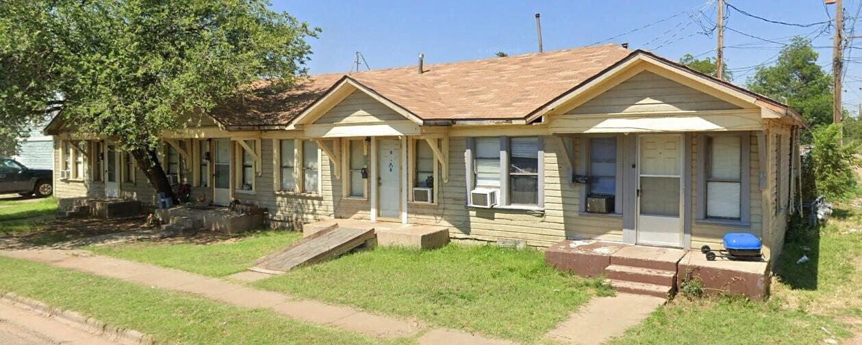 2208 Avenue T, Unit AD Lubbock, TX 79411 - Photo 2 of 2 a view of small white house with a yard and table and chairs under an umbrella