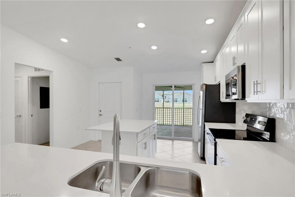 6047 Ellerston Way, Unit 2125 Ave Maria, FL 34142 - Photo 6 of 41 Kitchen with stainless steel appliances, tiled backsplash, quartz countertops