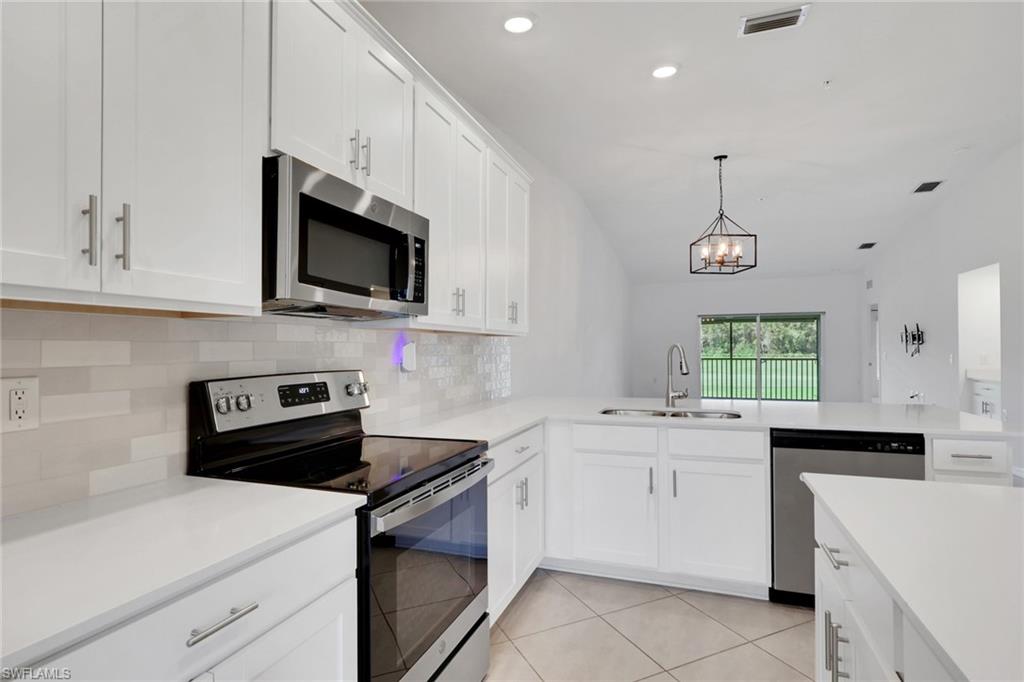 6047 Ellerston Way, Unit 2125 Ave Maria, FL 34142 - Photo 8 of 41 Kitchen with stainless steel appliances, tiled backsplash, quartz countertops