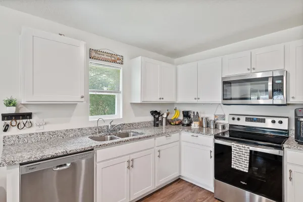 a kitchen with stainless steel appliances granite countertop a sink a stove a microwave and wooden cabinets