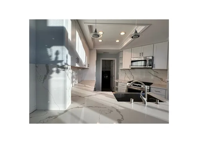 a kitchen with stainless steel appliances kitchen island granite countertop a sink refrigerator and microwave