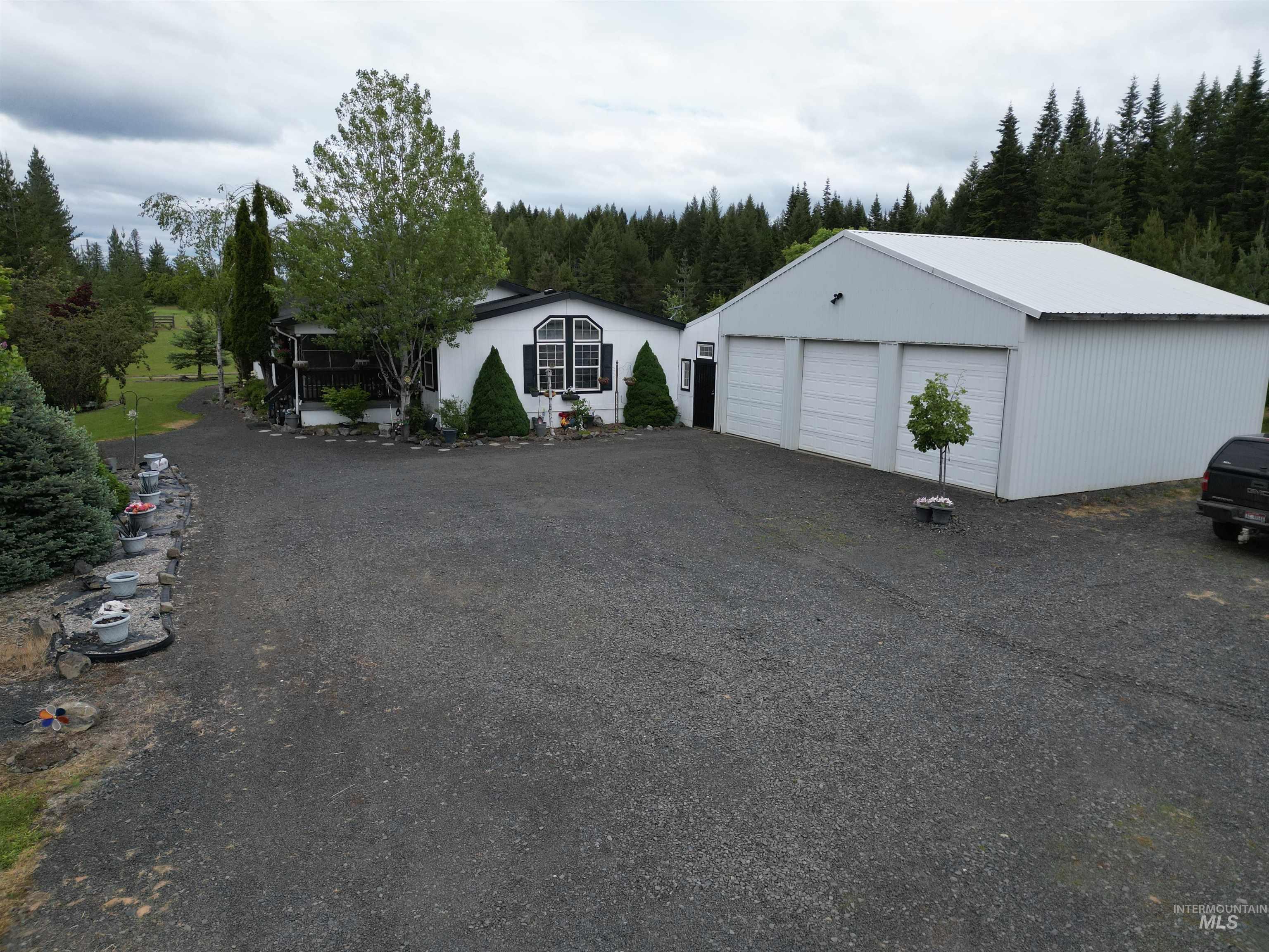 254 Lackey Road Weippe, ID 83553 - Photo 24 of 38 Spacious gravel driveway leading to a three-bay detached garage and a single-story residence with a covered porch