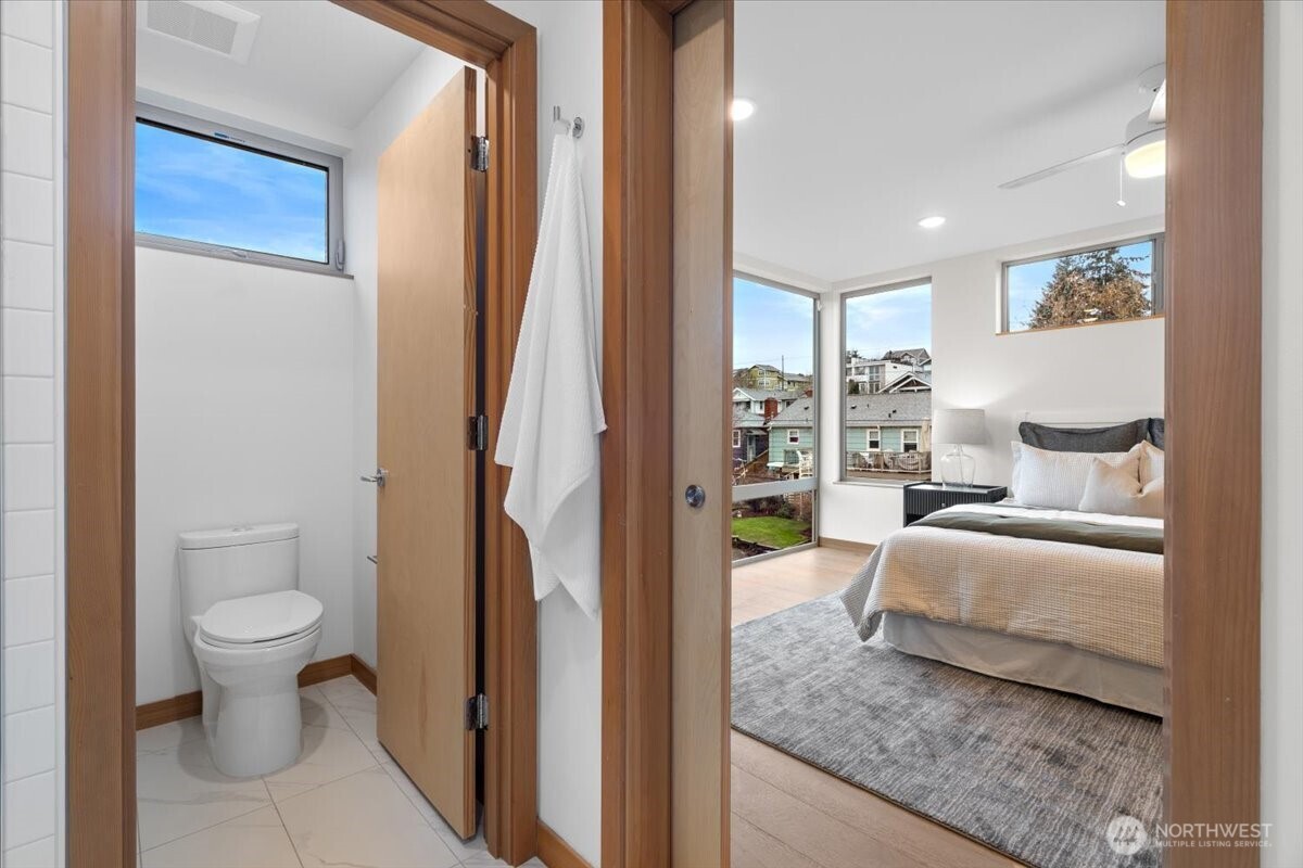 5017 Fauntleroy Way Southwest, Unit B Seattle, WA 98136 - Photo 13 of 24 a spacious bedroom with a bed and a painting on the wall