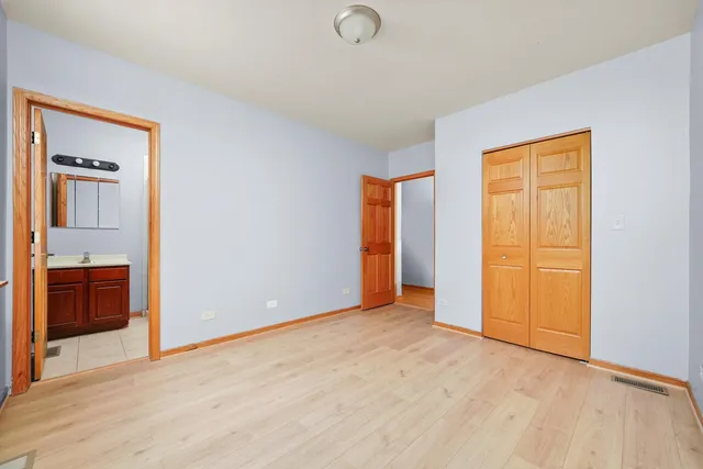 a view of an empty room with wooden floor and closet