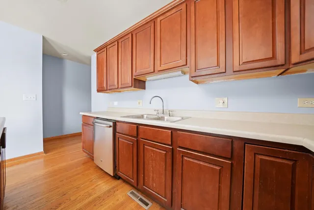 a kitchen with stainless steel appliances granite countertop wooden cabinets a sink and dishwasher with wooden floor