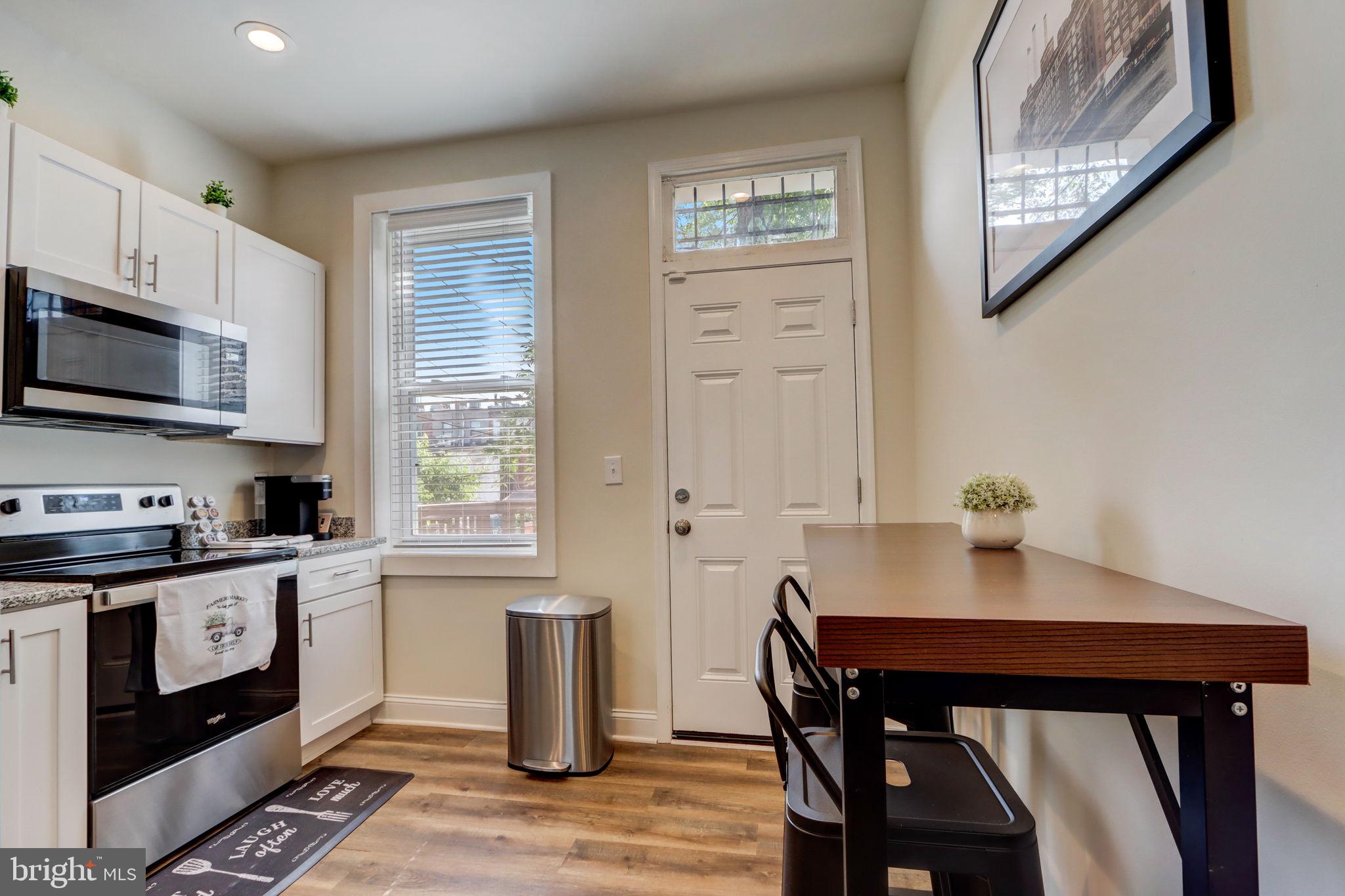 1628 North Calvert Street Baltimore, MD 21202 - Photo 11 of 63 a kitchen with stainless steel appliances a stove a sink cabinets and a dining table