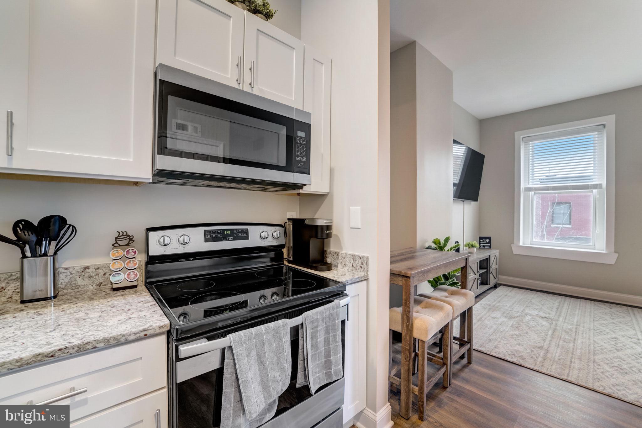 1628 North Calvert Street Baltimore, MD 21202 - Photo 57 of 63 a kitchen with granite countertop a stove a microwave a sink and cabinets