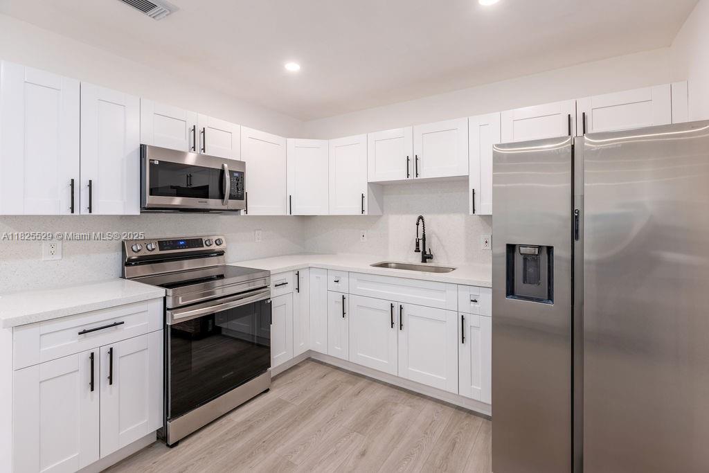 355 Southwest 17th Avenue Homestead, FL 33030 - Photo 7 of 21 a kitchen with stainless steel appliances granite countertop a stove a sink and a refrigerator