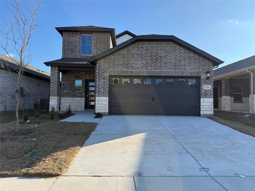 Brick and stone exterior with a covered porch entry, a multi-pane front door, and a two-car garage with windows