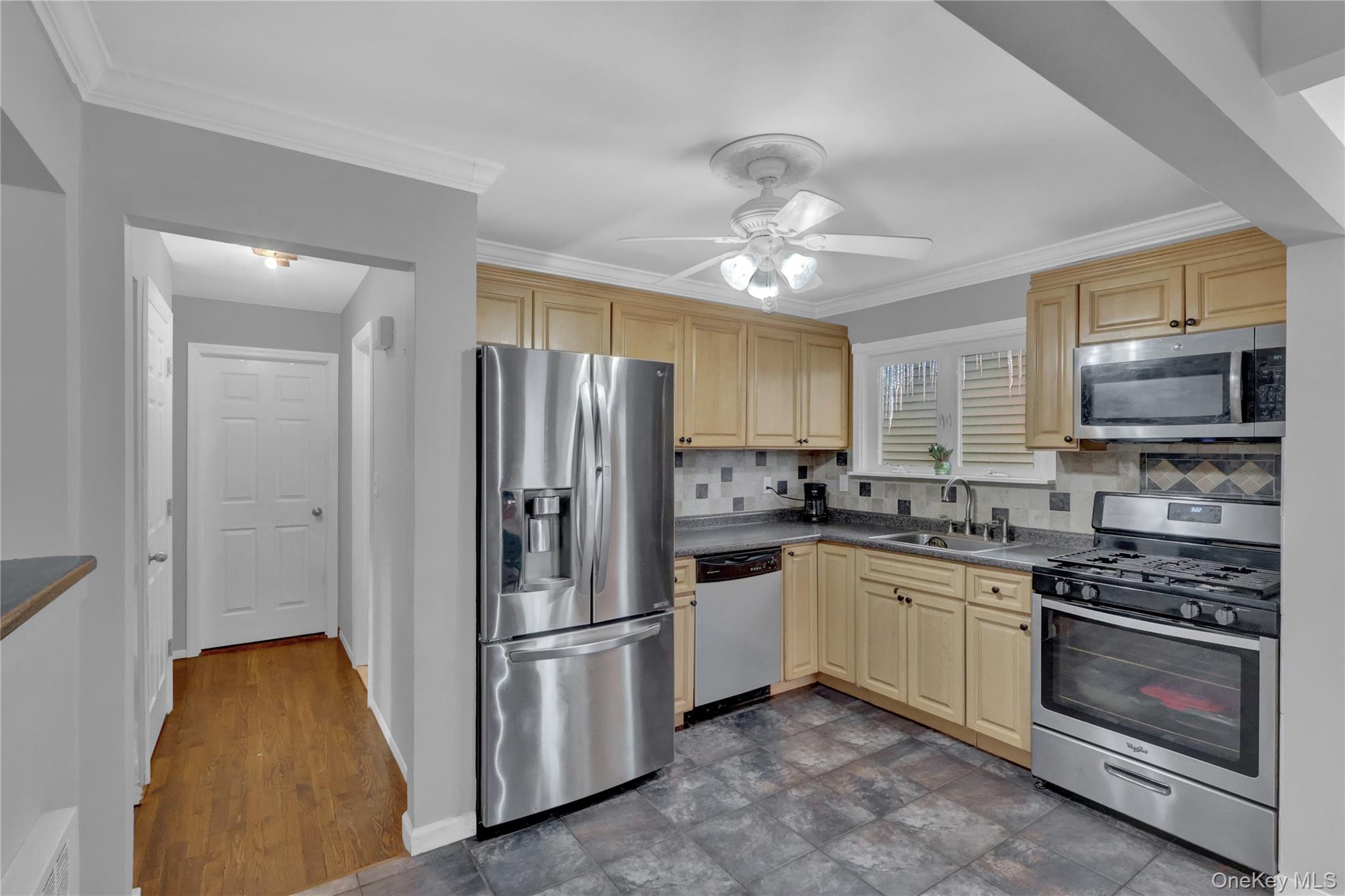 199 August Road North Babylon, NY 11703 - Photo 11 of 32 Kitchen with appliances with stainless steel finishes, tasteful backsplash, dark countertops, ornamental molding, and ceiling fan