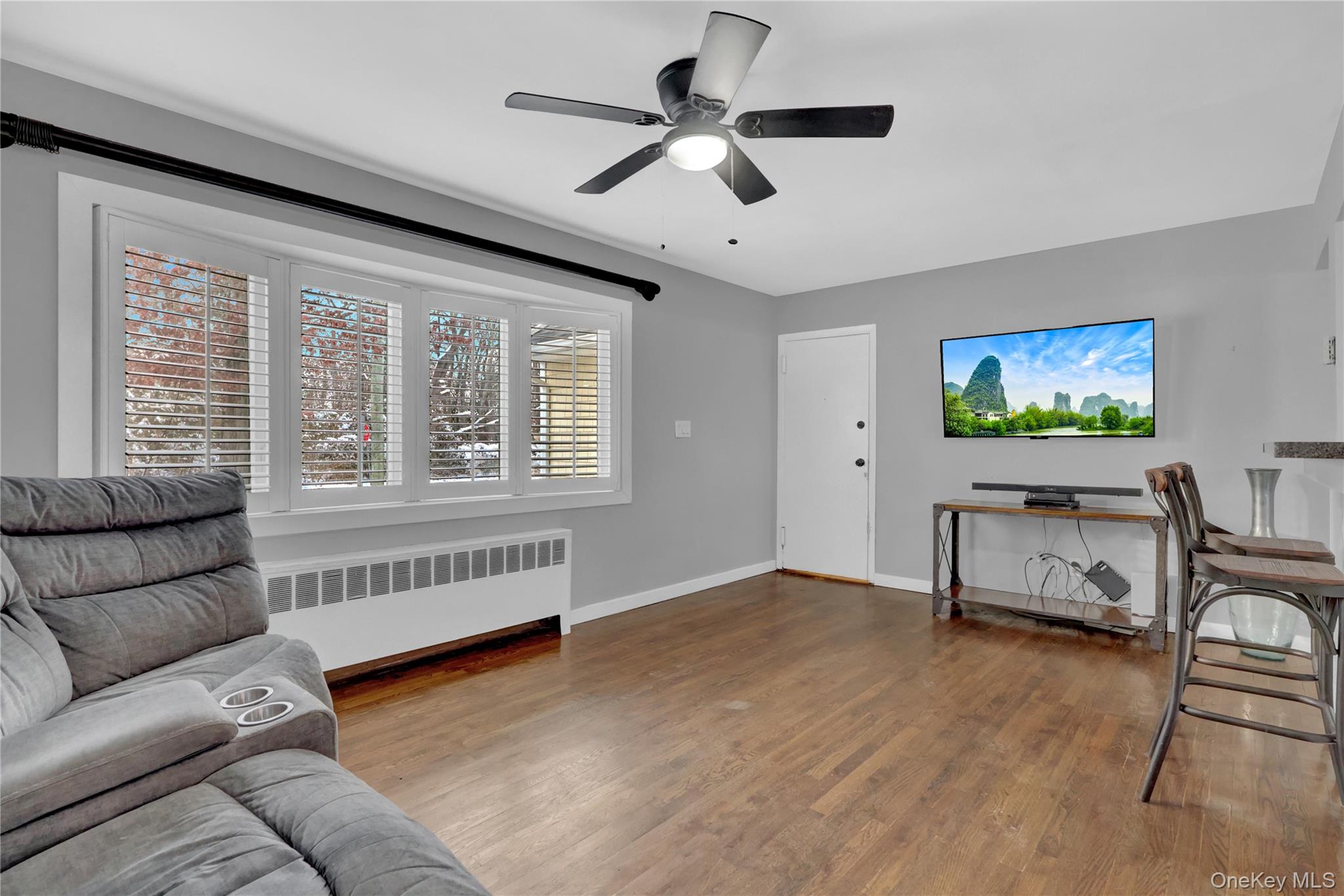 199 August Road North Babylon, NY 11703 - Photo 7 of 32 Living area featuring radiator heating unit, wood finished floors, and a ceiling fan