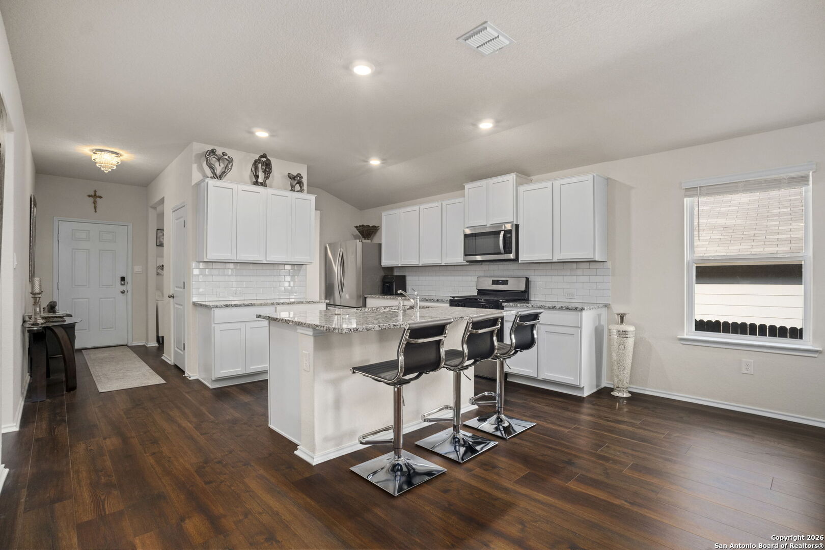 3658 Copper Willow Bulverde, TX 78163 - Photo 9 of 27 a kitchen with a sink a stove a refrigerator and white cabinets with wooden floor